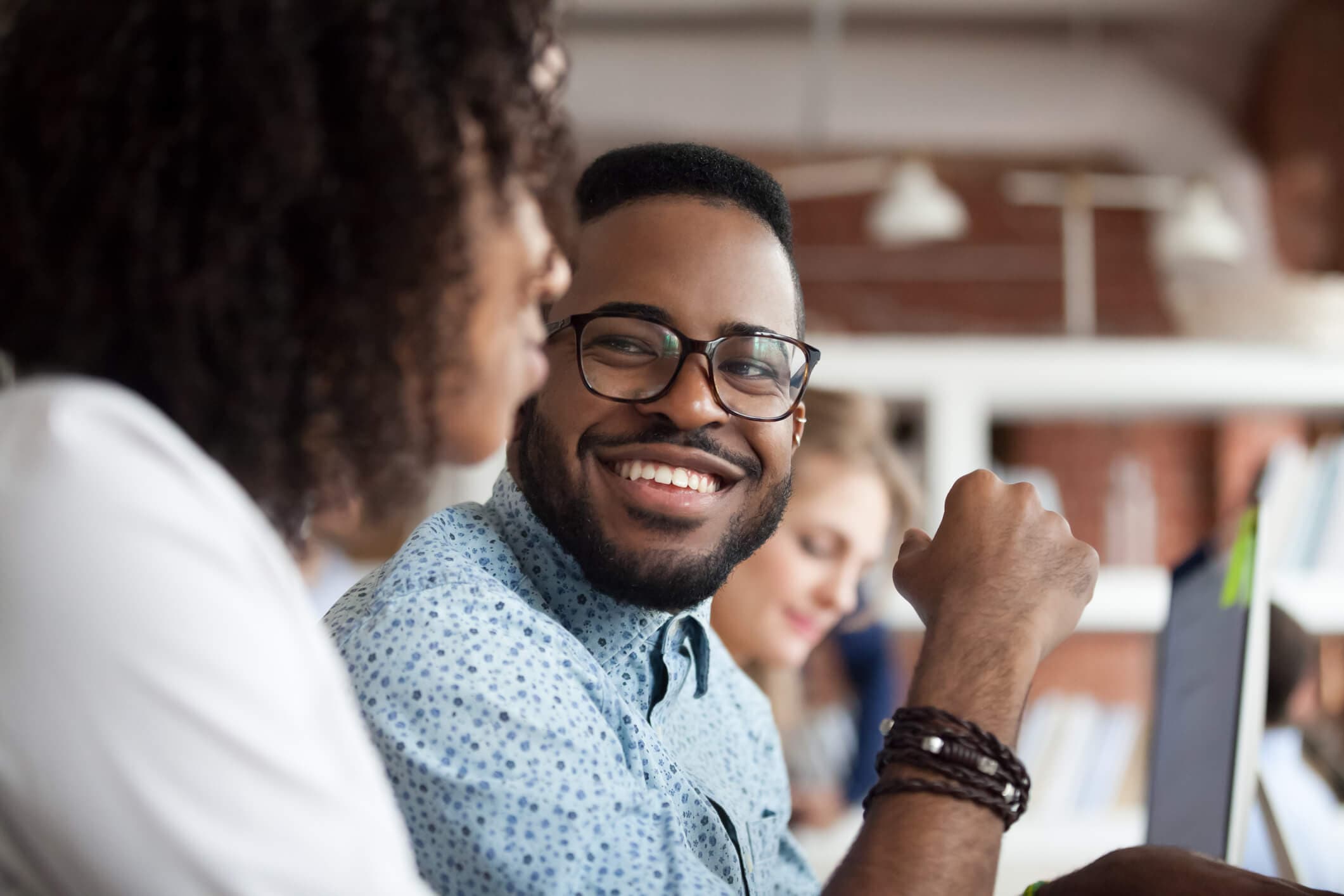 man and woman of color talking at computers