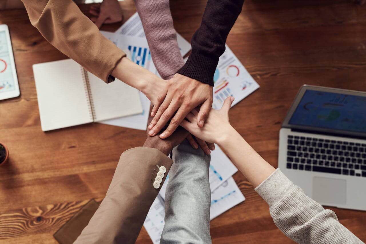 Close-up on colleagues joining hands in the center of a conference table
