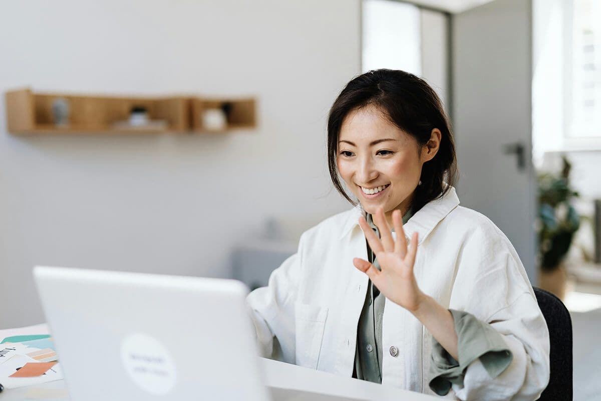 A woman logging on to her laptop and signing in to a remote team meeting