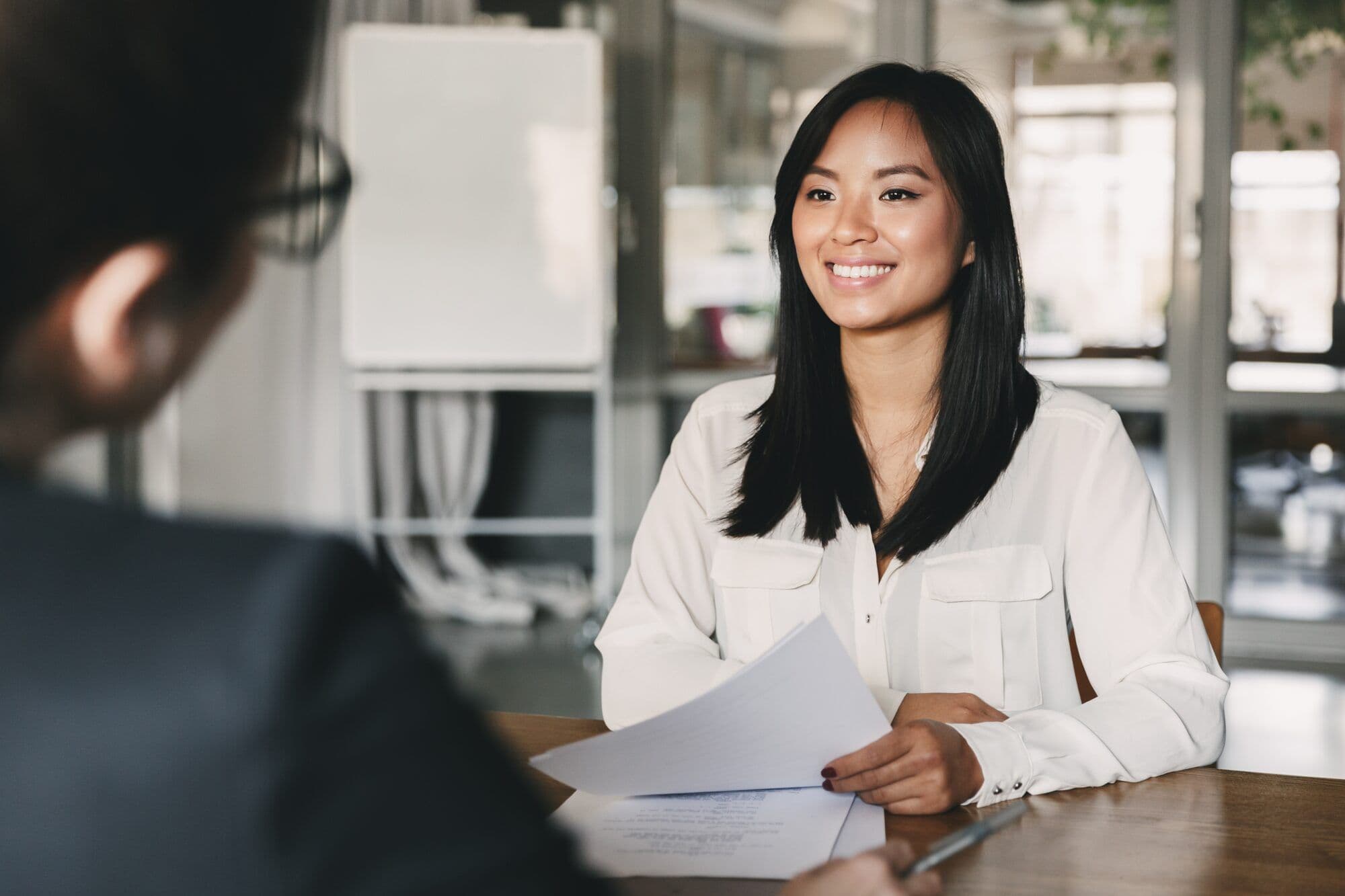 A smiling new hire talks with a colleague across a desk
